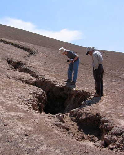 Photograph of scientists examining a large crack caused by an earthquake